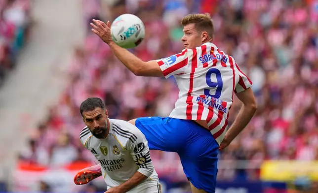 Atletico Madrid's Alexander Sorloth, right, vies for the ball with Real Madrid's Dani Carvajal during the Spanish La Liga soccer match between Atletico Madrid and Real Madrid at Metropolitano stadium, in Madrid, Spain, Saturday, Sept. 27, 2025. (AP Photo/Manu Fernandez)