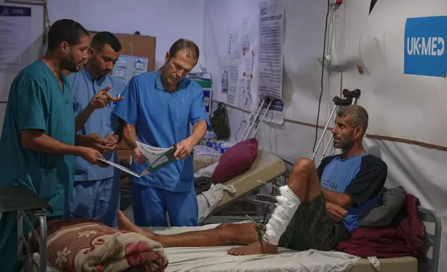 Dr. Paul Ransom of the British humanitarian medical NGO UK-Med, assisted by local medical staff, treats patients at a field hospital in Muwasi, near Khan Younis in the southern Gaza Strip, Saturday, Sept. 27, 2025. (AP Photo/Jehad Alshrafi)