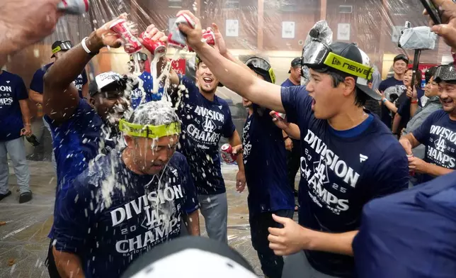 Los Angeles Dodgers two-way player Shohei Ohtani, right, celebrates with his teammates after the Dodgers clinched the National League West title against the Arizona Diamondbacks during a baseball game at Chase Field Thursday, Sept. 25, 2025, in Phoenix. (AP Photo/Darryl Webb)