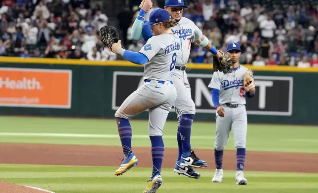 Los Angeles Dodgers first base Enrique Hernández (8) and Miquel Rojas, right, celebrate after the Dodgers clinched the National League West title against the Arizona Diamondbacks during a baseball game at Chase Field Thursday, Sept. 25, 2025, in Phoenix. (AP Photo/Darryl Webb)
