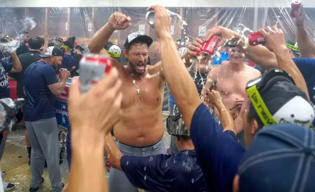 Los Angeles Dodgers pitcher Clayton Kershaw, center, celebrates with his teammates after the Dodgers clinched the National League West title against the Arizona Diamondbacks during a baseball game at Chase Field Thursday, Sept. 25, 2025, in Phoenix. (AP Photo/Darryl Webb)
