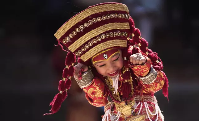 A young Newar girl, dressed to represent divine female energy, reacts as she waits for Kumari Puja, a ritual during which she would be worshipped, at Hanuman Dhoka, Basantapur Durbar Square, Kathmandu, Nepal, Friday, Sept. 5, 2025. (AP Photo/Niranjan Shrestha)