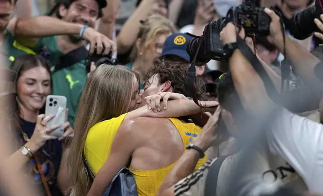 Sweden's Armand Duplantis kisses his girlfriend Desire Inglander after setting a new men's pole vault world record of 6.30 meters, at the World Athletics Championships in Tokyo, Monday, Sept. 15, 2025. (AP Photo/Matthias Schrader)