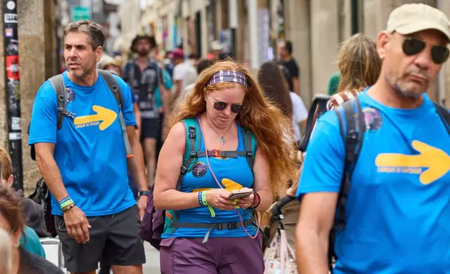 Pilgrims walk in Santiago de Compostela downtown, northwestern Spain, Thursday, Aug. 21, 2025. (AP Photo/Lalo Villar)