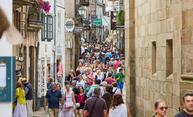 Pilgrims and tourists walk in Santiago de Compostela downtown, northwestern Spain, Thursday, Aug. 21, 2025. (AP Photo/Lalo Villar)