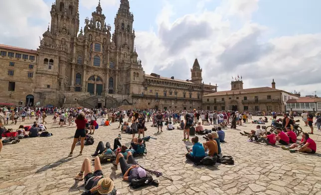 Pilgrims and tourists rest in front of the cathedral in Santiago de Compostela, northwestern Spain, Thursday, Aug. 21, 2025. (AP Photo/Lalo Villar)