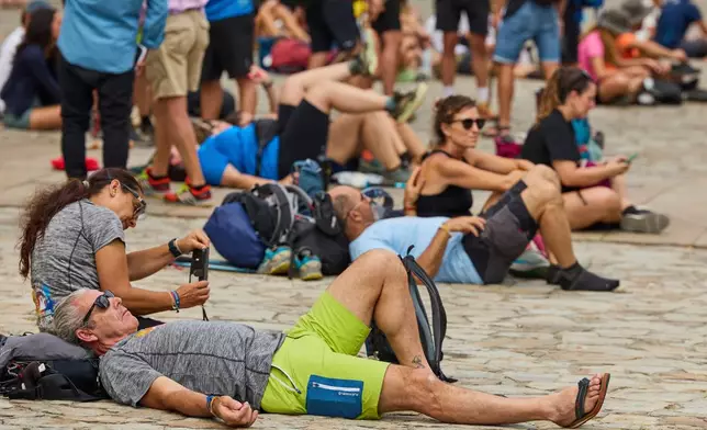 Pilgrims and tourists rest in front of the cathedral in Santiago de Compostela, northwestern Spain, Thursday, Aug. 21, 2025. (AP Photo/Lalo Villar)