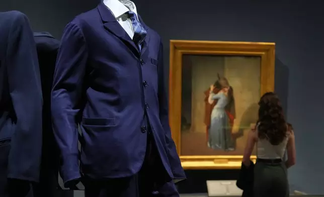 Giorgio Armani's creations are backdropped by the painting by Francesco Hayez titled "The Kiss", during the exhibition "Giorgio Armani - 50 Years" opened to the public at the Pinacoteca di Brera in Milan, Italy, Wednesday, Sept. 24 2025. (AP Photo/Antonio Calanni)