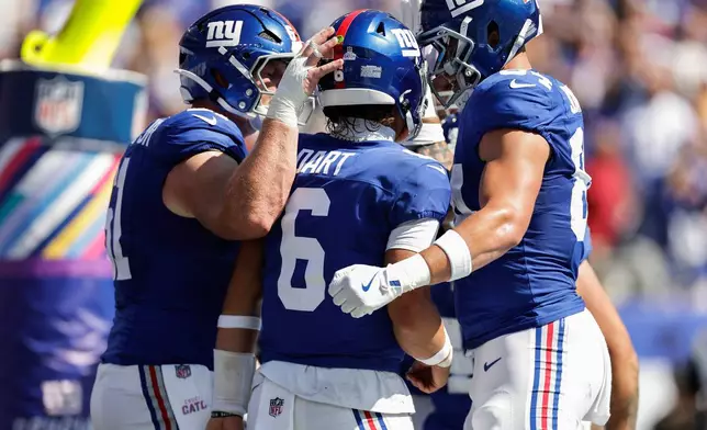 New York Giants quarterback Jaxson Dart (6) is congratulated by teammates after scoring a touchdown against the Los Angeles Chargers during the first quarter of an NFL football game, Sunday, Sept. 28, 2025, in East Rutherford, N.J. (AP Photo/Adam Hunger)