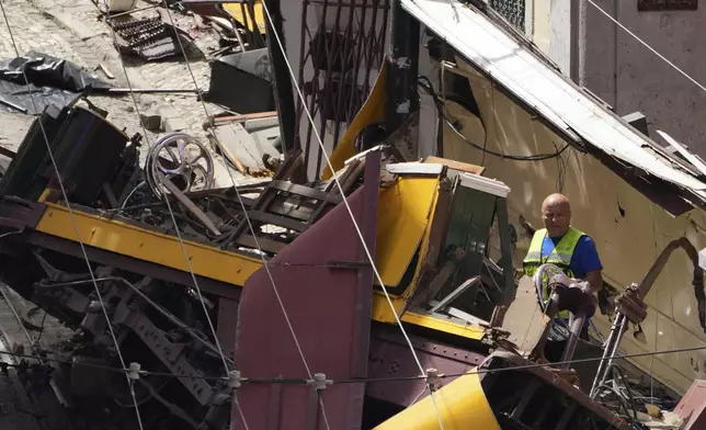 A person inspects the wreckage of a tourist streetcar that derailed and crashed in Lisbon, Portugal, Thursday, Sept. 4, 2025. (AP Photo/Armando Franca)
