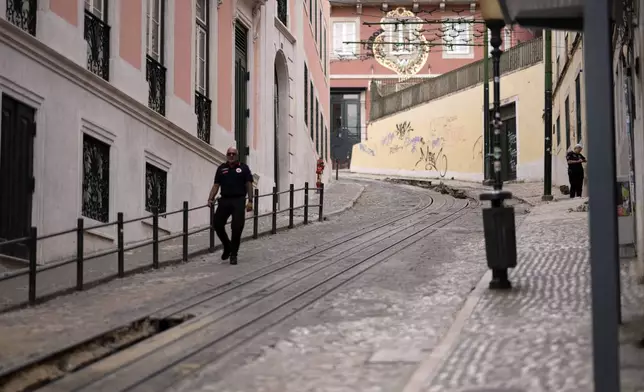 A police officer walks at the site where a tourist streetcar derailed and crashed in Lisbon, Portugal, Friday, Sept. 5, 2025. (AP Photo/Armando Franca)