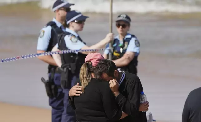A man is consoled at the site of a fatal shark attack at Dee Why Beach in Sydney, Australia, Saturday, Sept. 6, 2025. (AP Photo/Mark Baker)