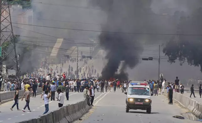 An ambulance drives past protesters burning tires to block streets during protests against social media ban and corruption in Kathmandu, Nepal, Tuesday, Sept. 9, 2025. (AP Photo/Niranjan Shrestha)