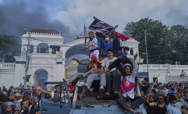 Protesters celebrate at the Singha Durbar, the seat of Nepal's government's various ministries and offices, after burning it down during a protest against a social media ban and corruption in Kathmandu, Nepal, Tuesday, Sept. 9, 2025. (AP Photo/Niranjan Shrestha)