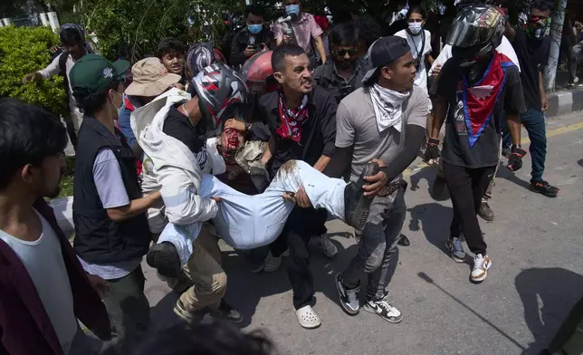An injured protester is taken to hospital by his friends during a protest in front of the parliament building in Kathmandu, Nepal, Monday, Sept. 8, 2025. (AP Photo/Niranjan Shrestha)
