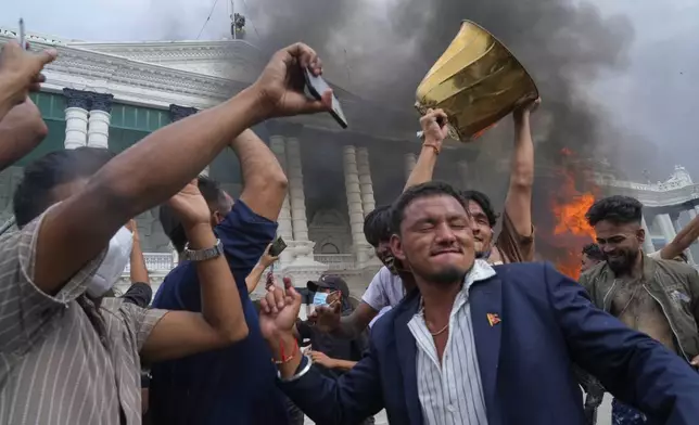 Protesters celebrate at the Singha Durbar, the seat of Nepal's government's various ministries and offices after burning it down during a protest against social media ban and corruption in Kathmandu, Nepal, Tuesday, Sept. 9, 2025. (AP Photo/Niranjan Shrestha)