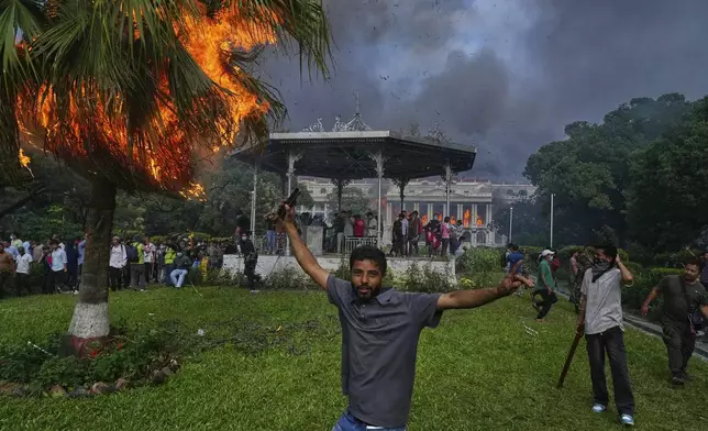 Protesters celebrate at the Singha Durbar, the seat of Nepal's government's various ministries and offices, after it was set on fire during a protest against a social media ban and corruption in Kathmandu, Nepal, Tuesday, Sept. 9, 2025. (AP Photo/Niranjan Shrestha)