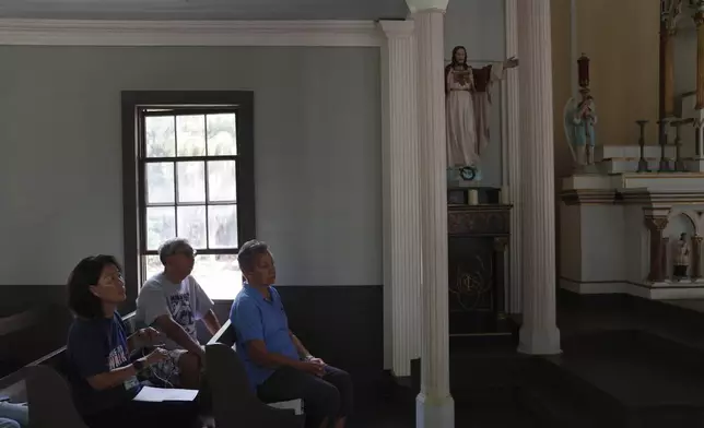FILE - Kyong Son Toyofuku, left, her husband, Lance Toyofuku, center, and sister Alicia Damien Lau, celebrate Mass at St. Philomena Church during a pilgrimage tour of Kalaupapa, Hawaii, July 18, 2023. (AP Photo/Jessie Wardarski, File)