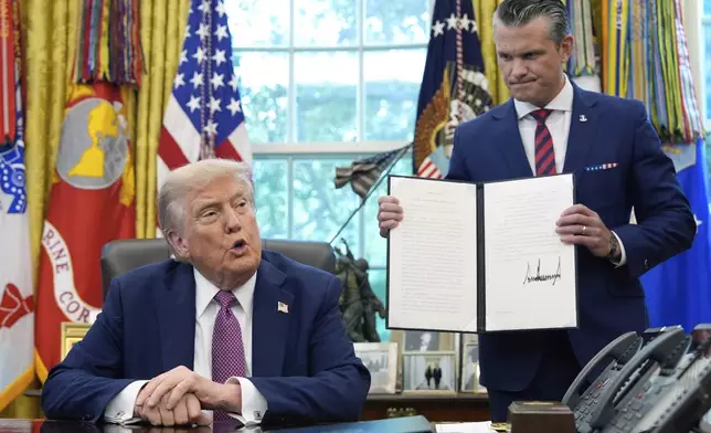 President Donald Trump speaks as Defense Secretary Pete Hegseth holds a signed executive order in the Oval Office of the White House, Friday, Sept. 5, 2025, in Washington. (AP Photo/Alex Brandon)