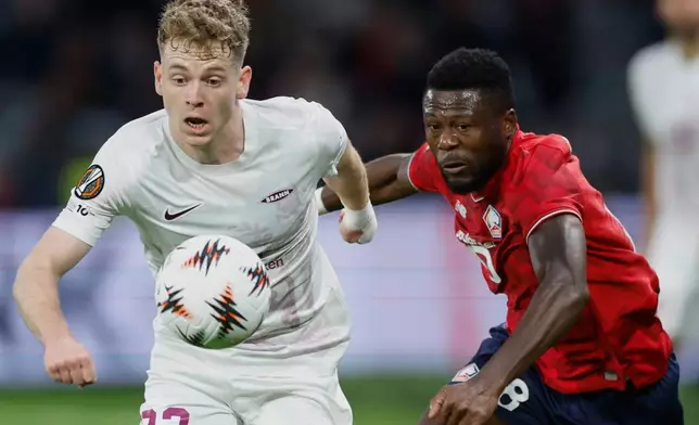 Brann's Saevar Atli Magnusson, left, fights for the ball with Lille's Chancel Mbemba, right, during the Europa League soccer match between Lille and Brann at the Pierre Mauroy stadium in Villeneuve d'Ascq, northern France, Thursday, Sept. 25, 2025. (AP Photo/Jean-Francois Badias)