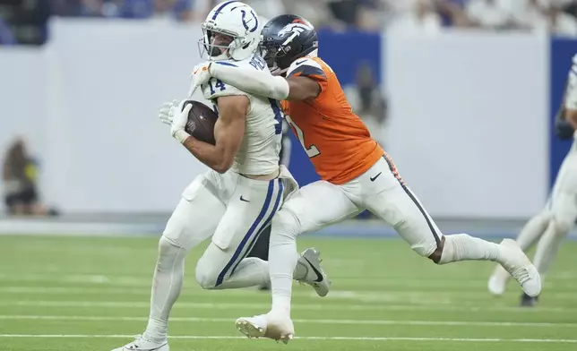 Indianapolis Colts wide receiver Alec Pierce (14) is tackled by Denver Broncos cornerback Pat Surtain II during the second half an NFL football game, Sunday, Sept. 14, 2025, in Indianapolis. (AP Photo/AJ Mast)
