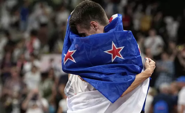 Gold medalist New Zealand's Hamish Kerr and silver medalist South Korea's Woo Sang-hyeok, background, embrace after the men's high jump final at the World Athletics Championships in Tokyo, Tuesday, Sept. 16, 2025. (AP Photo/Matthias Schrader)
