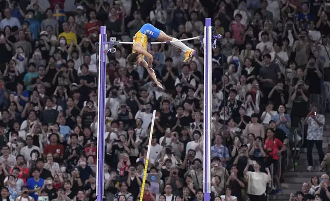 Spectators celebrate as Sweden's Armand Duplantis makes a clearance to break the world record after winning gold in the men's pole vault final at the World Athletics Championships in Tokyo, Monday, Sept. 15, 2025. (AP Photo/Petr David Josek)