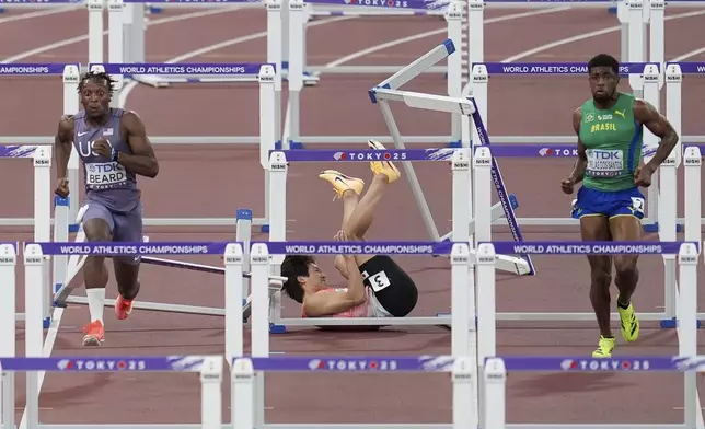 Japan's Shunsuke Izumiya, center, falls as United States' Dylan Beard and Brazil's Thiago Resende Ornelas Dos Santos compete in the men's 110 meters hurdles semifinal at the World Athletics Championships in Tokyo, Tuesday, Sept. 16, 2025. (AP Photo/Abbie Parr)