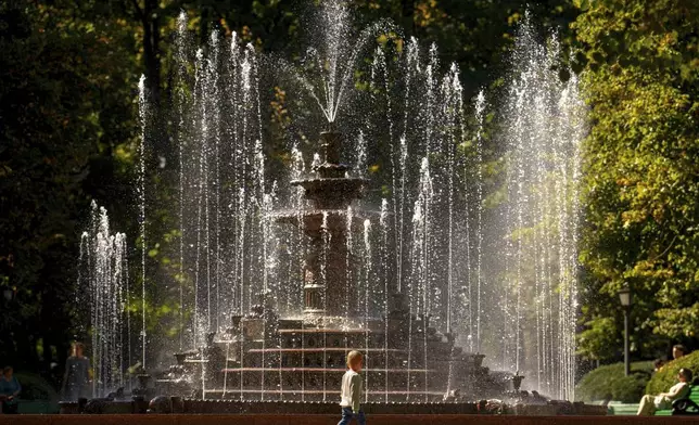 A child walks past a city fountain in a park in Chisinau, Moldova, Tuesday, Sept. 23, 2025. (AP Photo/Vadim Ghirda)