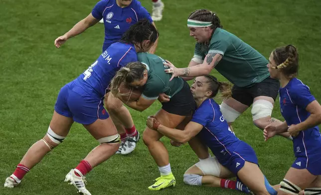 Ireland's Aoife Dalton, center, is tackled by France's captain Mane Feleu, left, and her teammate Joanna Grisez during a Women's Rugby World Cup 2025 quarterfinal match between France and Ireland, in Exeter, England, Sunday, Sept. 14, 2025. (AP Photo/Alastair Grant)