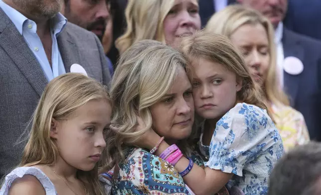 Carrie Hanna stands with her daughters Hunter, right, and Harper, left, and other parents and family of children who died at Camp Mystic, as they watch Texas Gov. Greg Abbott sign camp safety bills, Friday, Sept. 5, 2025, in Austin, Texas. (AP Photo/Eric Gay)