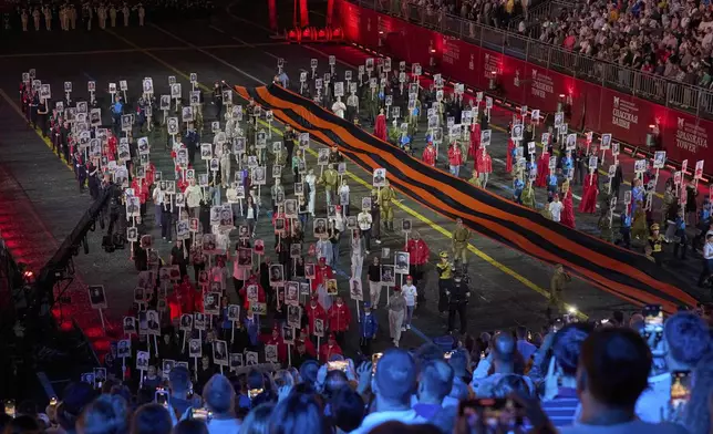 Russian soldiers carry a giant St. George ribbon, a symbol of Soviet participation in World War II and portraits of fallen soldiers, during the closing ceremony of the Spasskaya Tower International Military Music Festival in Red Square in front of the St. Basil Cathedral in Moscow, Russia, on Sunday, Aug. 31, 2025. (AP Photo/Alexander Zemlianichenko)