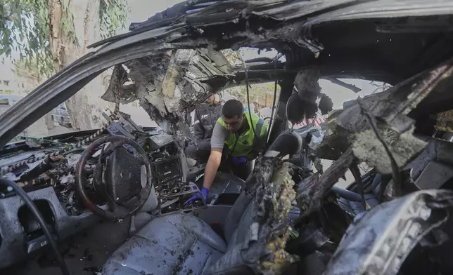 A civil defense worker inspects a damaged car hit the previous day in an Israeli drone strike that killed four members of the same family in Bint Jbeil, southern Lebanon, Monday, Sept. 22, 2025. (AP Photo/Mohammed Zaatari)