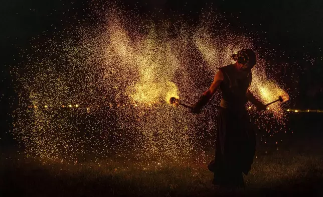 People participate in fire rituals during the Autumn Equinox celebration in Vilnius, Lithuania, Monday, Sept. 22, 2025. (AP Photo/Mindaugas Kulbis)