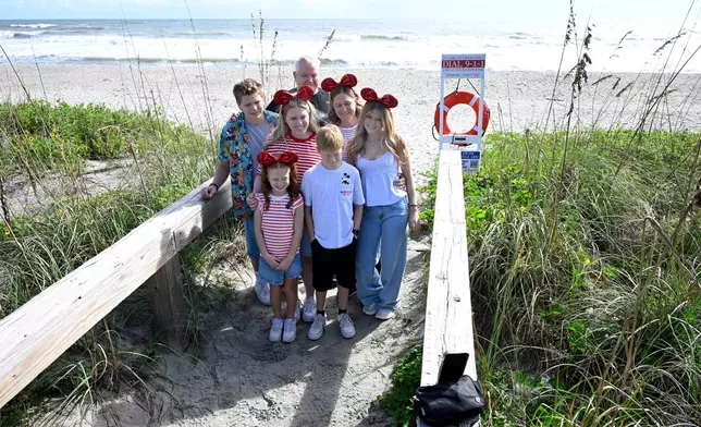 Brian and Carrie Archibald, of Gilbert, Ariz., make a selfie photo with their children at Blockhouse Beach before heading out on a Disney cruise as Tropical Imelda passes offshore, kicking up the surf, Monday, Sept. 29, 2025, at Patrick Space Force Base, Fla. (AP Photo/Phelan M. Ebenhack)