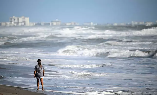 Maiko Russell walks along the sand as Tropical Imelda passes offshore, kicking up the surf at Blockhouse Beach, Monday, Sept. 29, 2025, at Patrick Space Force Base, Fla. (AP Photo/Phelan M. Ebenhack)