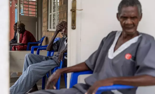 Older residents of a care facility sit outside their rooms in Magogo, Uganda, Friday, Nov. 15, 2024. The facility is on the campus of a school operated by the NGO Reach One Touch One Ministries for children who are cared for by their grandparents. (AP Photo/David Goldman)