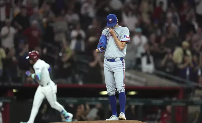 Texas Rangers pitcher Hoby Milner, right, pauses on the pitcher's mound after giving up a three-run home run to Arizona Diamondbacks' Ketel Marte, left, during the seventh inning of a baseball game Tuesday, Sept. 2, 2025, in Phoenix. (AP Photo/Ross D. Franklin)