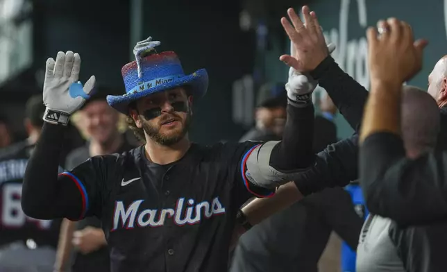 Miami Marlins' Connor Norby is greeted in the dugout after hitting a solo home run off Texas Rangers pitcher Jack Leiter during the sixth inning of a baseball game Saturday, Sept. 20, 2025, in Arlington, Texas. (AP Photo/Julio Cortez)