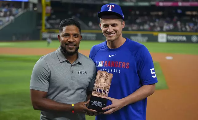 Texas Rangers shortstop Corey Seager, right, is presented with the Rangers' Roberto Clemente Award nomination by former Ranger Elvis Andrus prior to a baseball game against the Miami Marlins Saturday, Sept. 20, 2025, in Arlington, Texas. (AP Photo/Julio Cortez)