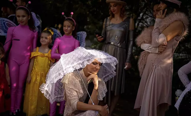 Entertainers wearing vintage styled outfits wait to take part in a parade marking the day when the Romanian capital was first mentioned in historical records, 566 years ago, in Bucharest, Romania, Saturday, Sept. 20, 2025. (AP Photo/Andreea Alexandru)