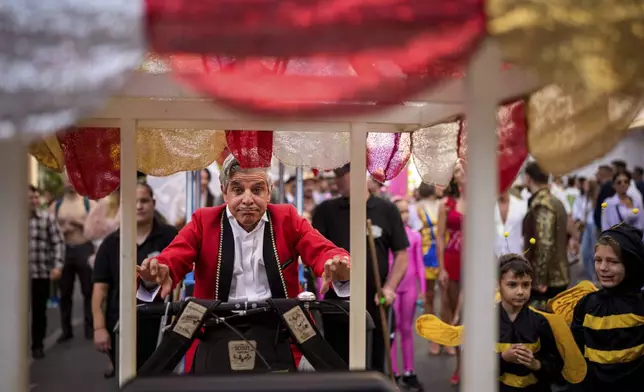 An artist of the Bucharest Metropolitan Circus pushes a vintage ice cream cart during a parade marking the day when the Romanian capital was first mentioned in historical records, 566 years ago, in Bucharest, Romania, Saturday, Sept. 20, 2025. (AP Photo/Andreea Alexandru)