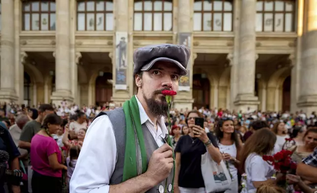 A man wearing vintage styled outfit holds a carnation during an event marking the day when the Romanian capital was first mentioned in historical records, 566 years ago, in Bucharest, Romania, Saturday, Sept. 20, 2025. (AP Photo/Andreea Alexandru)
