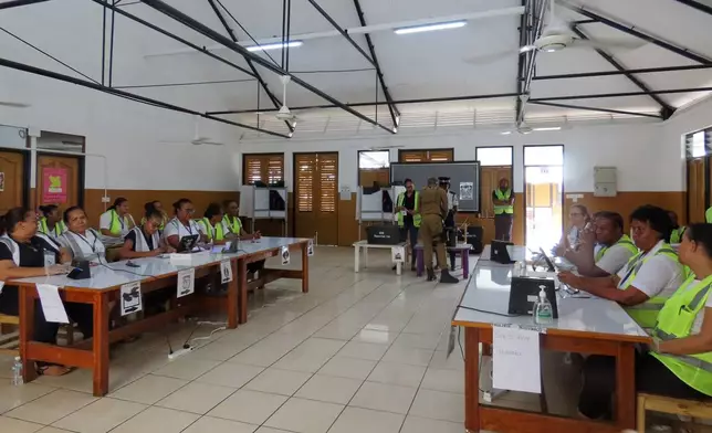 Electoral commission staff monitor voting, inside a classroom as people cast their votes at the polling station at English River School in Victoria, Seychelles, Thursday, Sept. 25, 2025. (AP Photo/Emilie Chetty)