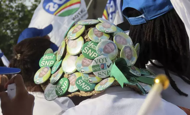A supporter wears a hat pinned with the symbols of the Seychelles National Party, a former opposition political party, during a campaign rally at Freedom Square in Victoria, Seychelles, Sunday, Sep. 21, 2025. (AP Photo/Emilie Chetty)