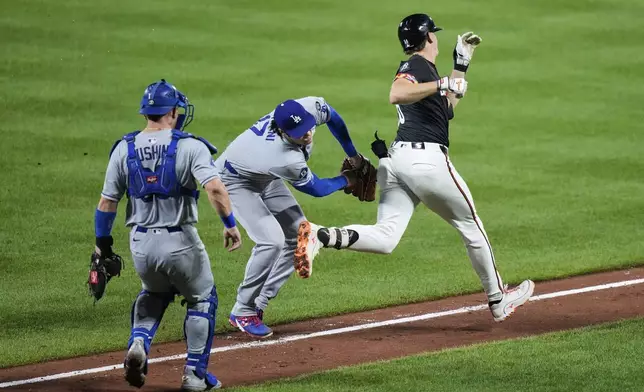 Los Angeles Dodgers starting pitcher Shohei Ohtani, center, tags out Baltimore Orioles' Coby Mayo, right, during the third inning of a baseball game, Friday, Sept. 5, 2025, in Baltimore. (AP Photo/Stephanie Scarbrough)