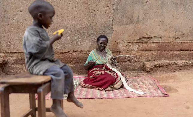 Tereza Nabunya, 75, weaves a mat from papyrus leaves outside her home, Friday, Nov. 15, 2024, in Nkulagirire, Uganda. (AP Photo/David Goldman)T