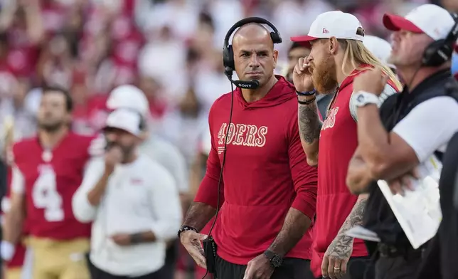 FILE - San Francisco 49ers tight end George Kittle, second from right, takes a whiff of a smelling salt stick next to defensive coordinator Robert Saleh, middle, on the sideline during the first half of an NFL preseason football game against the Los Angeles Chargers, Saturday, Aug. 23, 2025, in Santa Clara, Calif. (AP Photo/Godofredo A. Vásquez, File)