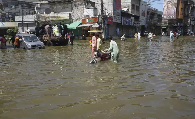 Residents navigate through a flooded road following by heavy rains, in Gujrat, Pakistan, Thursday, Sept. 4, 2025. (AP Photo/A. Rizvi)