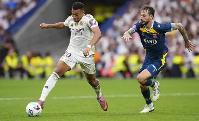 Real Madrid's Kylian Mbappe, left, and Espanyol's Fernando Calero challenge for the ball during the Spanish La Liga soccer match between Real Madrid and Espanyol at the Santiago Bernabeu stadium in Madrid, Spain, Saturday, Sept. 20, 2025. (AP Photo/Manu Fernandez)
